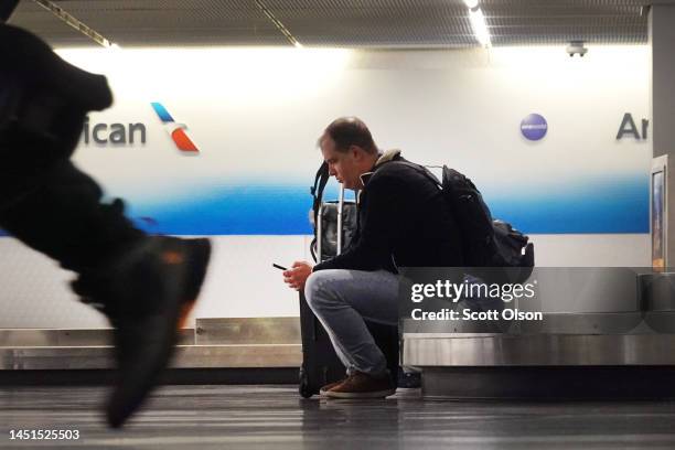 Traveler sits in the baggage claim area at O'Hare International Airport on December 22, 2022 in Chicago, Illinois. A winter weather system bringing...