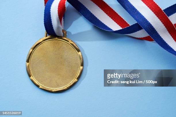 top view of gold medal against blue background,malaysia - medal photos et images de collection