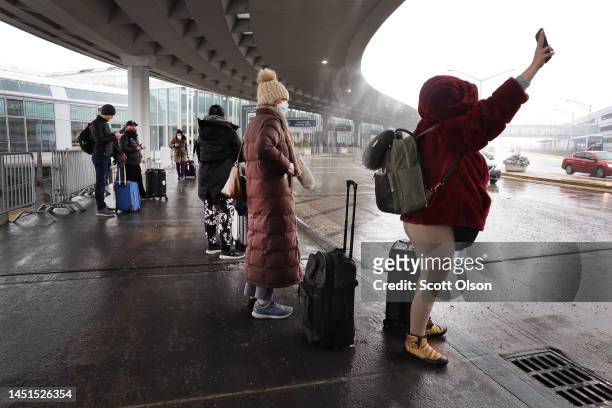 Travelers wait for ride shares at O'Hare International Airport on December 22, 2022 in Chicago, Illinois. A winter weather system bringing snow, high...