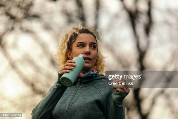 mujer descansando y bebiendo agua después de entrenar al aire libre - sports training fotografías e imágenes de stock