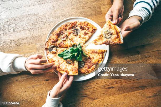 two friends having a pizza on a wooden table - pizza stock pictures, royalty-free photos & images