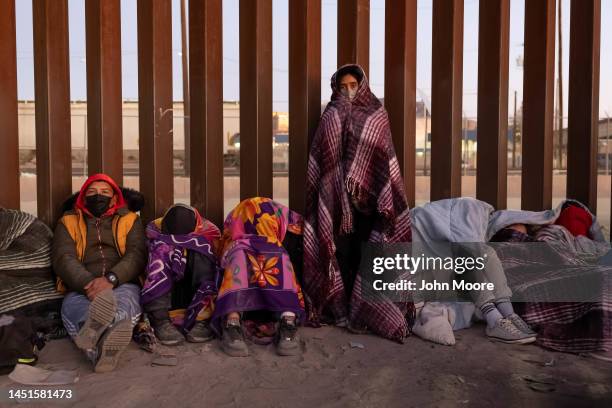 Immigrants bundle up against the cold after spending the night outside along the U.S.-Mexico border fence on December 22, 2022 in El Paso, Texas. A...