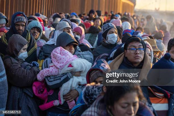 Immigrants bundle up against the cold after spending the night camped alongside the U.S.-Mexico border fence on December 22, 2022 in El Paso, Texas....