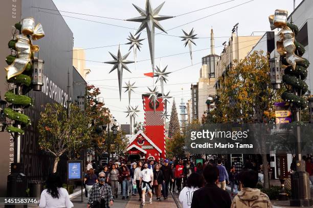 People walk through The Grove shopping mall during the holiday shopping season, three days before Christmas, on December 22, 2022 in Los Angeles,...
