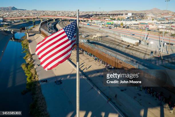 An aerial view of the American flags flying over an international bridge as immigrants line up next to the U.S.-Mexico border fence to seek asylum on...