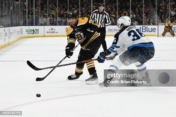 Connor Clifton of the Boston Bruins passes the puck past Morgan Barron of the Winnipeg Jets during the first period at the TD Garden on December 22,...