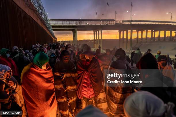 Immigrants keep warm by a fire at dawn after spending a night alongside the U.S.-Mexico border fence on December 22, 2022 in El Paso, Texas. A spike...