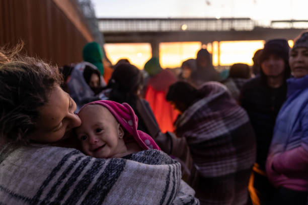 Venezuelan immigrant Stephanie holds her daughter Hannie, 10 months, after spending the night camped alongside the U.S.-Mexico border fence on...