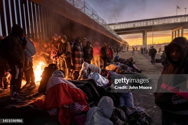 Immigrants warm to a fire at dawn after spending the night outside next to the U.S.-Mexico border fence on December 22, 2022 in El Paso, Texas. A...