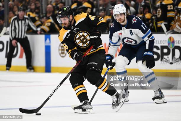 David Krejci of the Boston Bruins skates with the puck in front of Adam Lowry of the Winnipeg Jets during the second period at the TD Garden on...