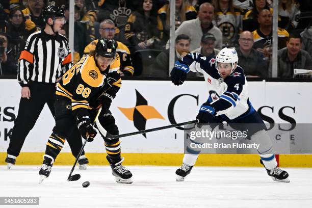 Neal Pionk of the Winnipeg Jets defends David Pastrnak of the Boston Bruins during the second period at the TD Garden on December 22, 2022 in Boston,...