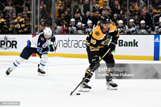 David Pastrnak of the Boston Bruins skates on a breakaway in front of Neal Pionk of the Winnipeg Jets during the first period at the TD Garden on...