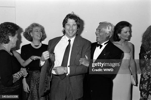 Actor Richard Gere shows designer Giorgio Armani his suit label, as guests watch the exchange, with socialite Lee Radziwill.