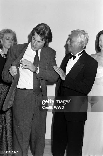 Actor Richard Gere shows designer Giorgio Armani his suit label, as guests watch the exchange.