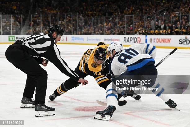 Patrice Bergeron of the Boston Bruins and Pierre-Luc Dubois of the Winnipeg Jets take a face-off during the third period at the TD Garden on December...