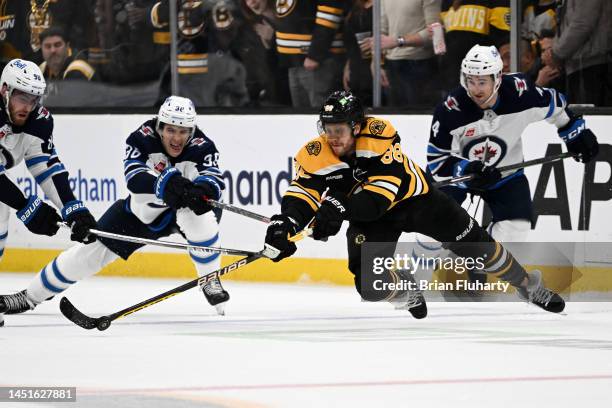 David Pastrnak of the Boston Bruins and Morgan Barron of the Winnipeg Jets battle for the puck during the third period at the TD Garden on December...