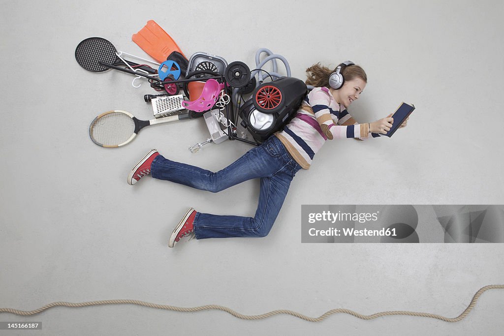 Girl with gadgets reading book