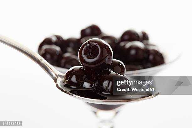 preserved amarena cherry in glass bowl and spoon, close up - black cherries stock-fotos und bilder