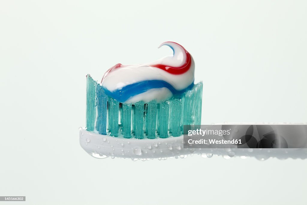 Electric toothbrush with toothpaste against white background, close up