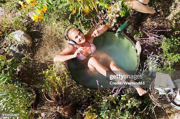 austria, salzburg, flachau, young woman sitting in tun with water and listening music - thinktank stock pictures, royalty-free photos & images