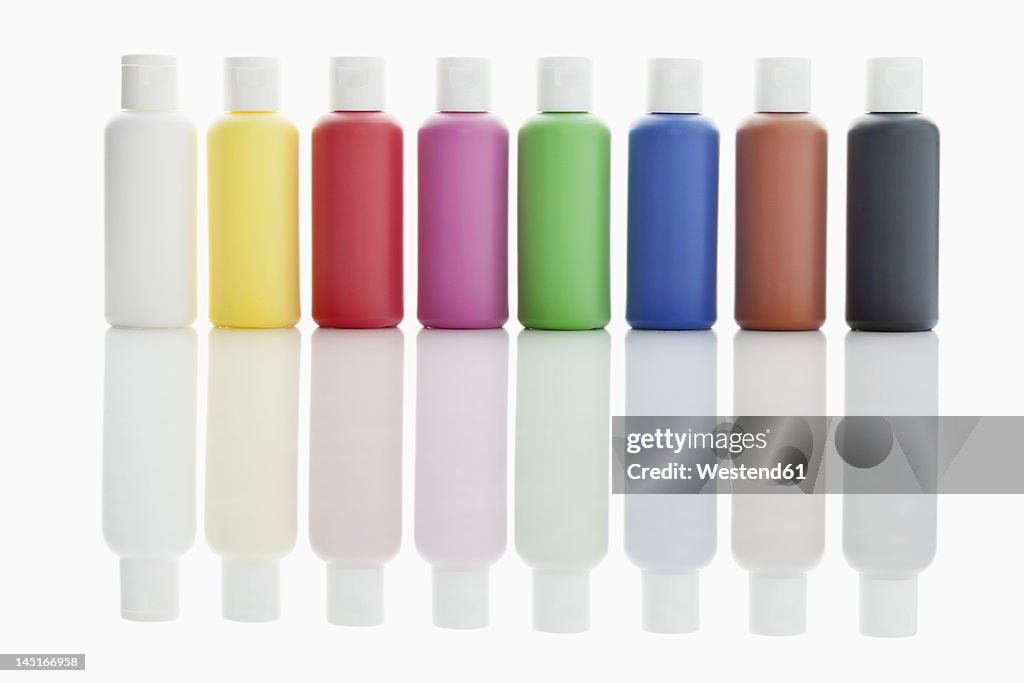 Row of acrylic color bottles on white background