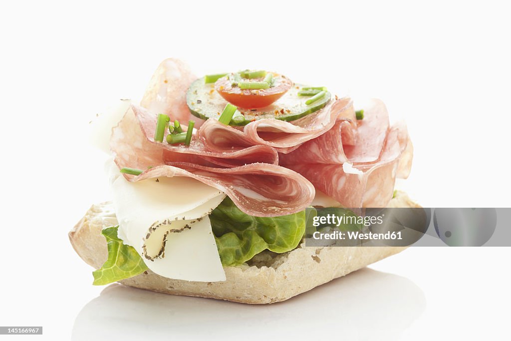 Bread roll with salami, cheese, tomatoes, lettuce on white background