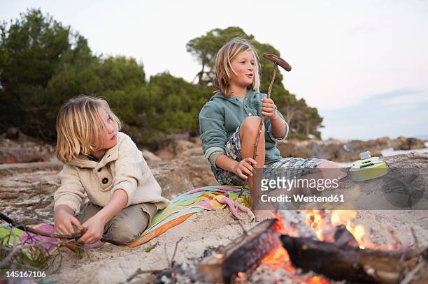 spain, mallorca, children barbecueing sausages on beach - children only stock-fotos und bilder