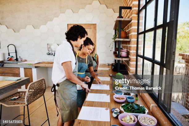 medium wide shot of chef and student discussing recipe during cooking class - advice woman travel traveling stock pictures, royalty-free photos & images
