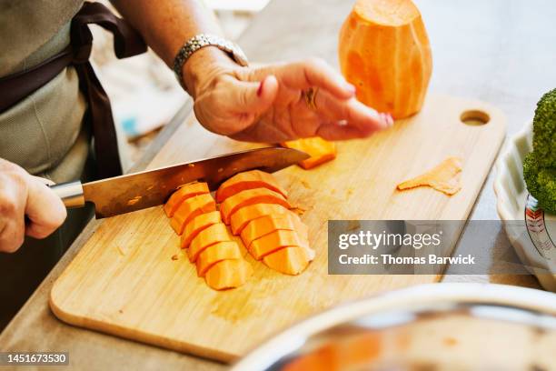 close up shot of woman chopping sweet potatoes during cooking class - zoete aardappel stockfoto's en -beelden