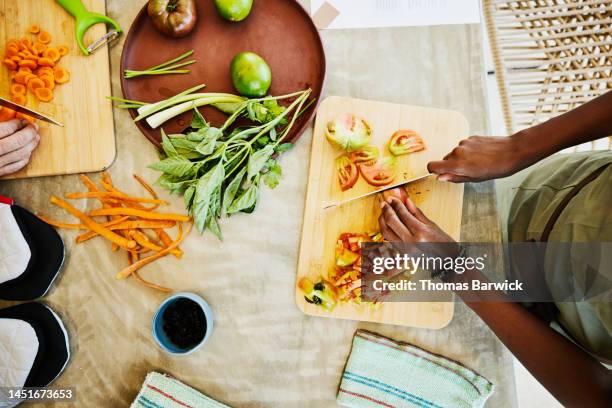 medium overhead shot of woman slicing tomatoes during cooking class - snijplank stockfoto's en -beelden