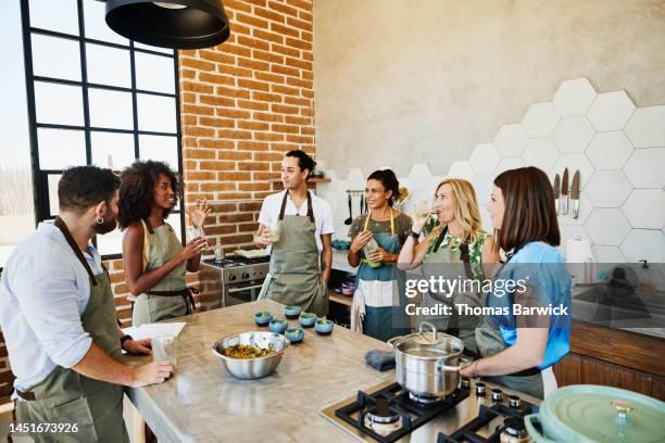 wide shot of cooking class sampling fresh organic juice in kitchen - 料理教室 ストックフォトと画像