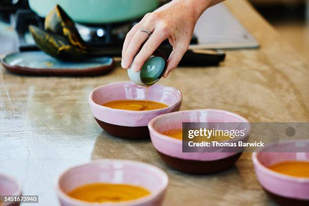 close up shot of woman adding olive oil to sweet potato ginger soup - olive oil bowl stock pictures, royalty-free photos & images