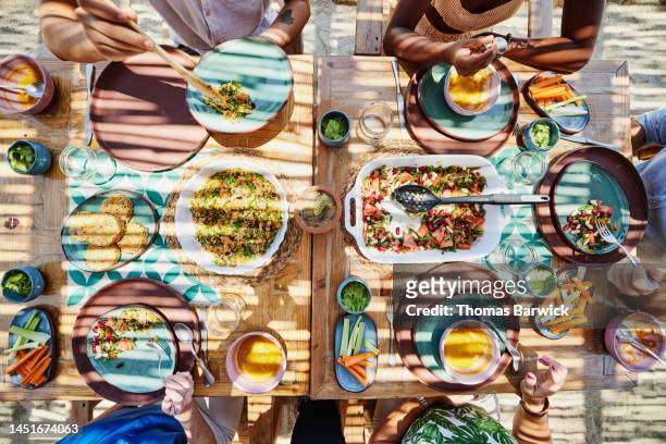 medium overhead shot of friends sharing lunch at outdoor table - lunch top view stock pictures, royalty-free photos & images