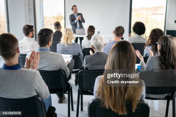 back view of entrepreneurs applauding on education event in board room. - professional seminar stock pictures, royalty-free photos & images