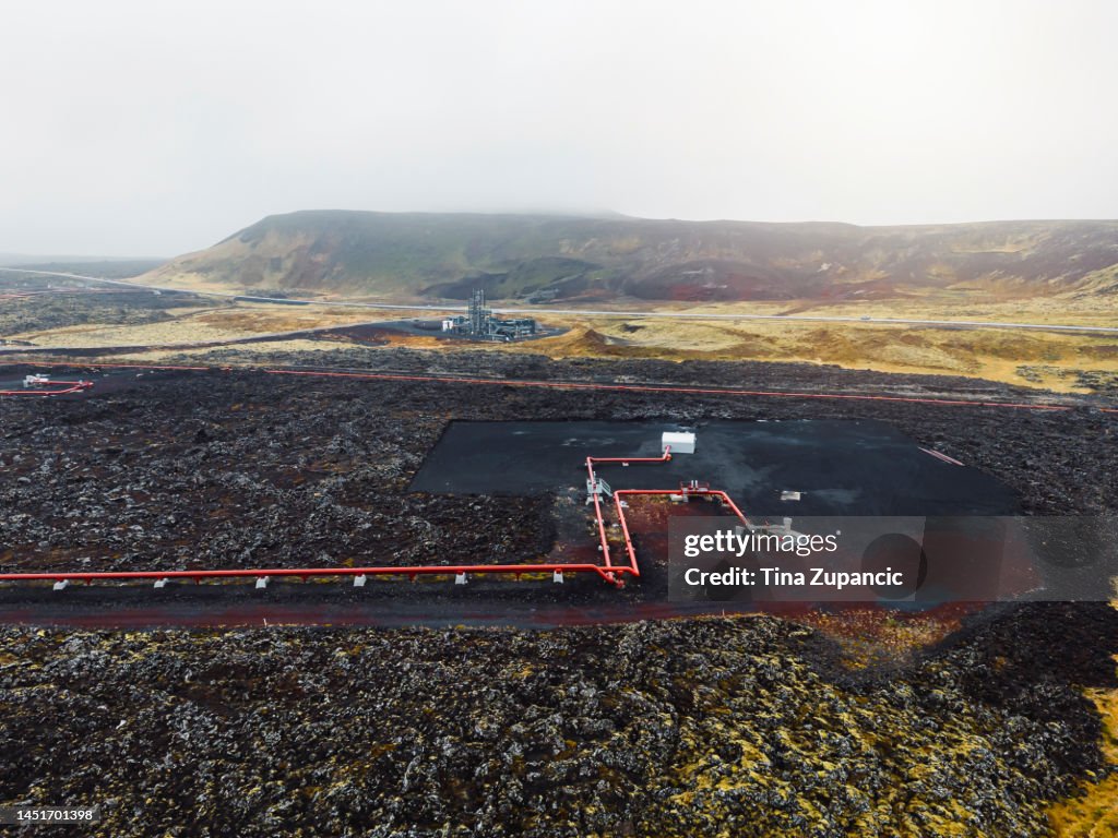 Red pipes standing out from black volcanic soil - Geothermal power plant in Iceland