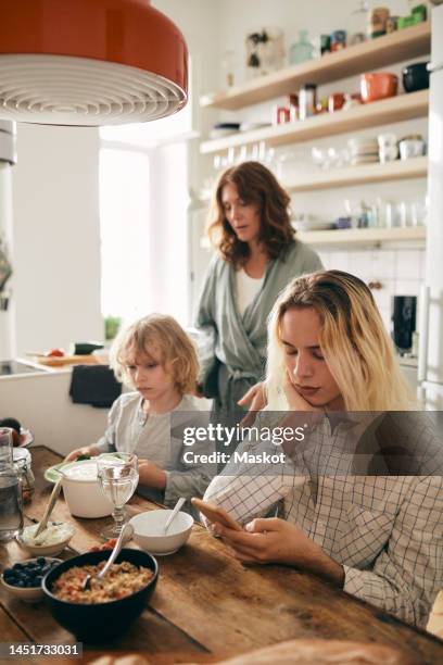 transgender person and brother with breakfast sitting at table in home - lgbt mobile foto e immagini stock