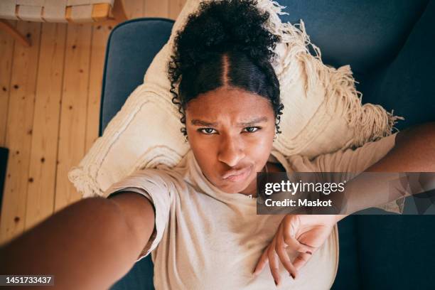 portrait of girl puckering lips while taking selfie lying on sofa at home - beicinho imagens e fotografias de stock
