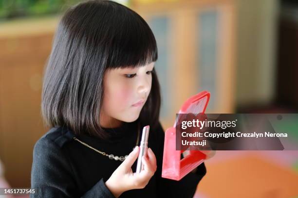 little girl putting make up - kid putting finger in mouth stock-fotos und bilder