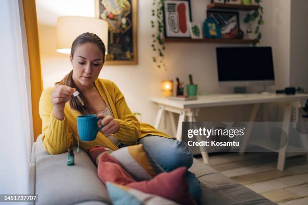 a woman uses a pipette to pour cannabis oil into tea - cbd oil stock pictures, royalty-free photos & images