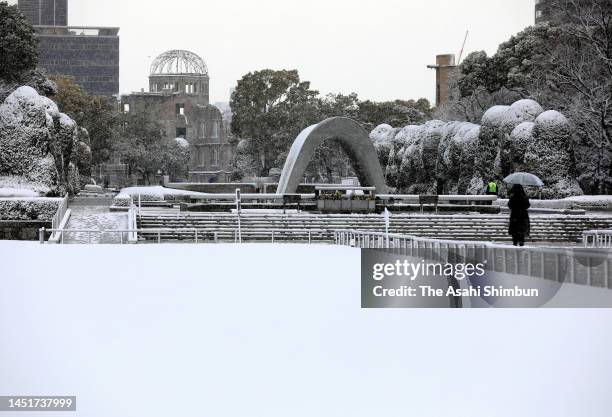 Woman pray in front of the cenotaph at snow capped Hiroshima Peace Memorial Park on December 23, 2022 in Hiroshima, Japan. Projections of 24-hour...