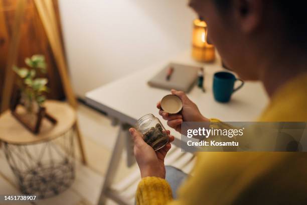 unrecognizable woman reads inscription on glass bottle with cannabis - illegal drugs at work stock pictures, royalty-free photos & images