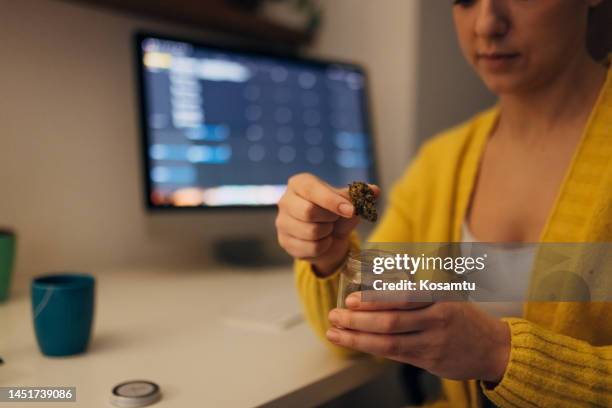 woman holding a bottle of medical marijuana in her hands - illegal drugs at work stock pictures, royalty-free photos & images