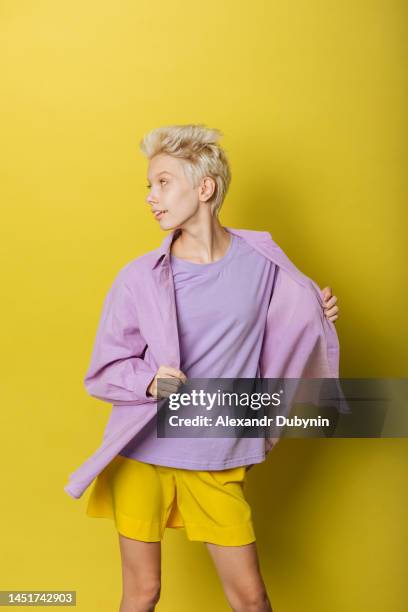 young beautiful teen girl posing in colored summer clothes on a yellow background - multi colored shirt foto e immagini stock