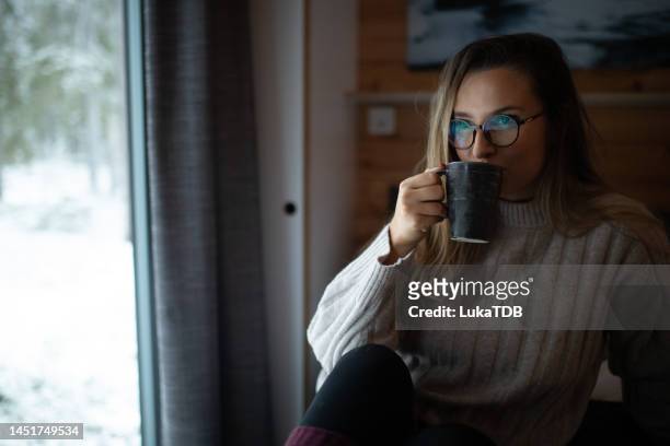 a beautiful woman drinks her favorite tea and warms herself in the cottage - the natural world stock pictures, royalty-free photos & images
