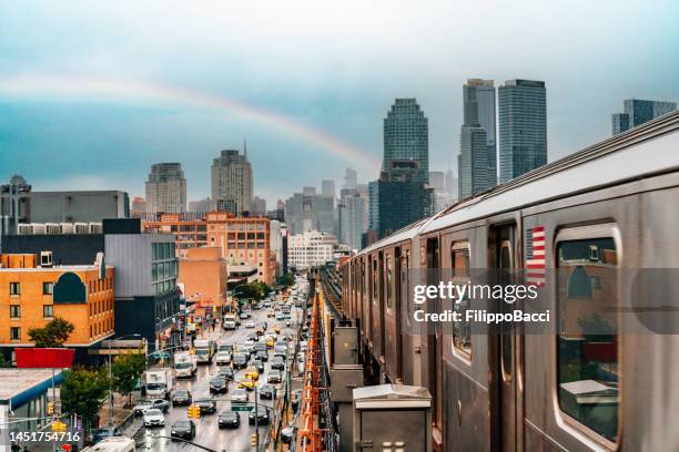 new york city subway train is approaching an elevated subway station in queens - queens new york city stock pictures, royalty-free photos & images