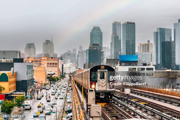 el tren subterráneo de la ciudad de nueva york se acerca a una estación de metro elevada en queens - queens new york city fotografías e imágenes de stock