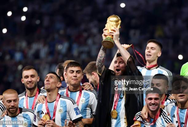 Lionel Messi of Argentina - holding the World Cup and wearing a traditional black robe called bisht - and teammates celebrate during the trophy...