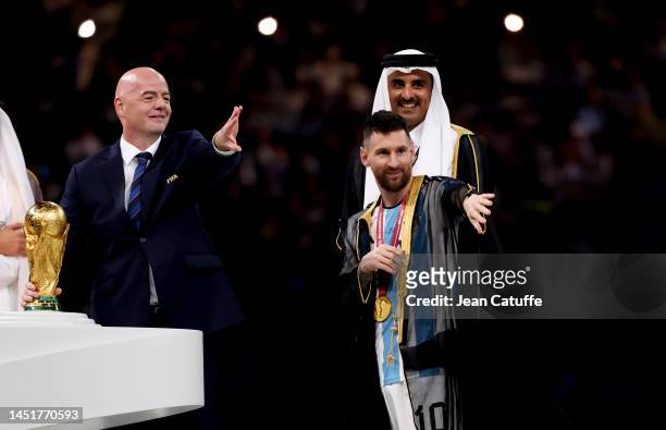 President Gianni Infantino, Emir of Qatar Sheikh Tamim bin Hamad Al Thani and Lionel Messi of Argentina wearing a traditional black robe called bisht...