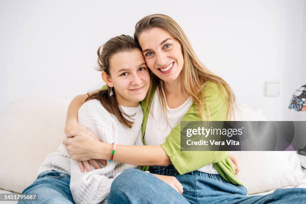 portrait of caucasian mother hugging teen daughter in bed - 13 years old girl in jeans stock pictures, royalty-free photos & images