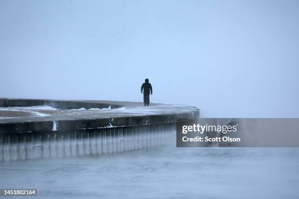 Man walks along Lake Michigan at sunrise as temperatures hover about -6 degrees on December 22, 2022 in Chicago, Illinois. Sub-zero temperatures are...